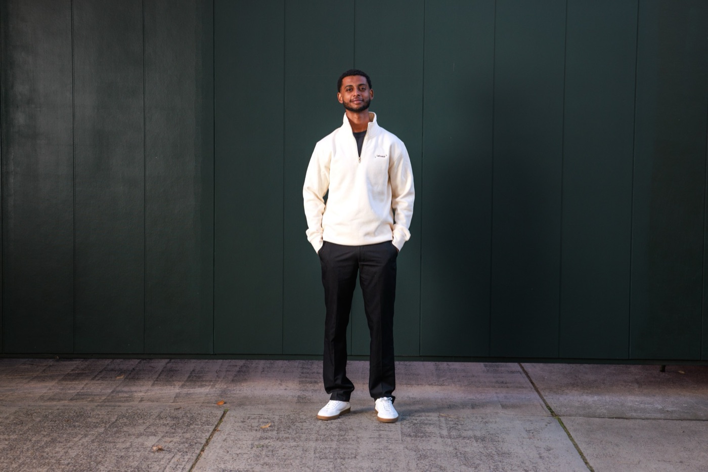 Ezana Yohala standing in front of a dark green wall